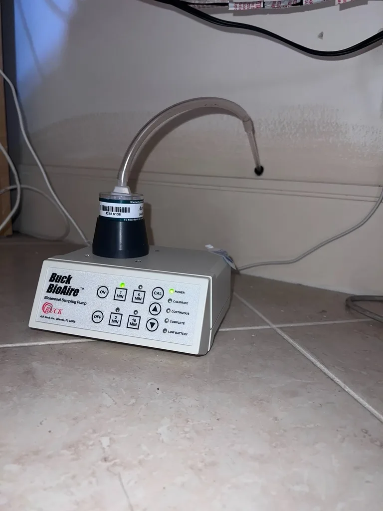 Buck BioAire bioaerosol air sampling pump set up on the floor with a spore trap cassette during an inspection