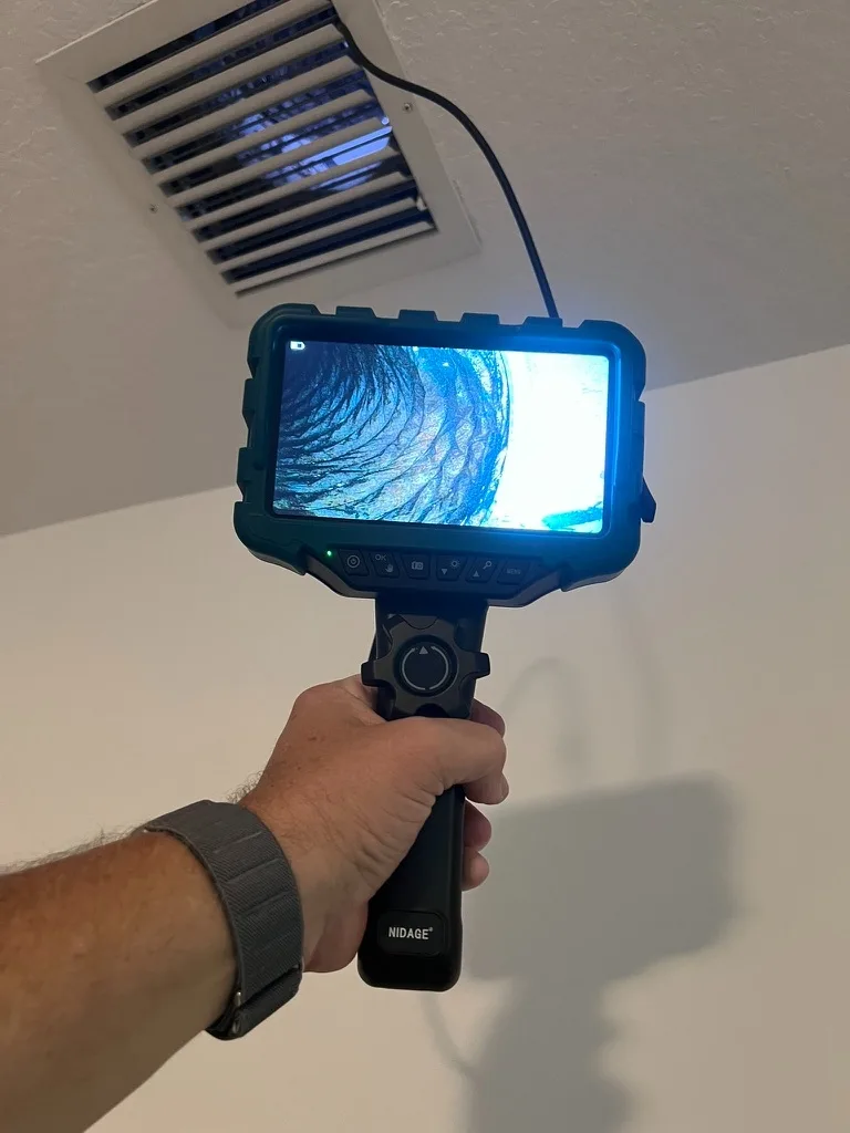 Borescope inspection camera showing the inside of an HVAC duct on its screen during a mold inspection