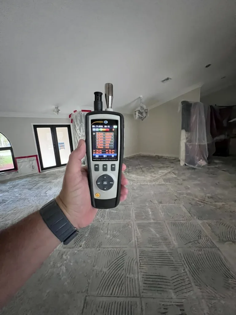 Home Enviro inspector holding a laser particle counter inside a property being assessed for airborne particulates