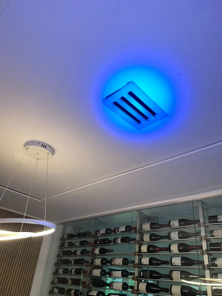 Ultraviolet inspection light illuminating an HVAC ceiling vent to reveal contamination in a wine room