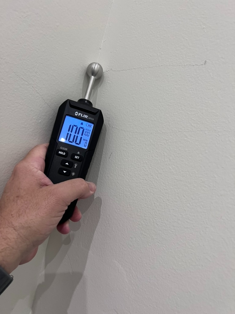 Digital moisture meter reading on affected wall in Hialeah, FL
