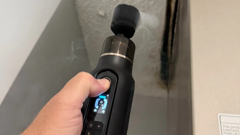 Inspector using a handheld smoke device to assess air movement near an interior building component
