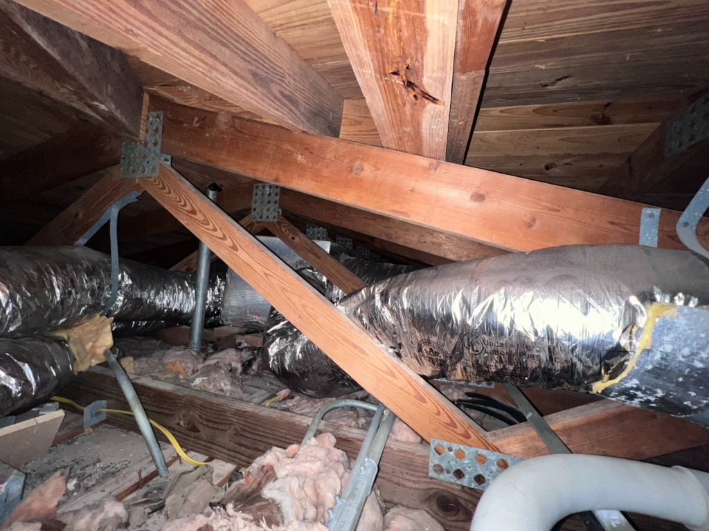 Attic rafters and insulated ductwork viewed during a Home Enviro attic inspection, showing staining on a roof beam