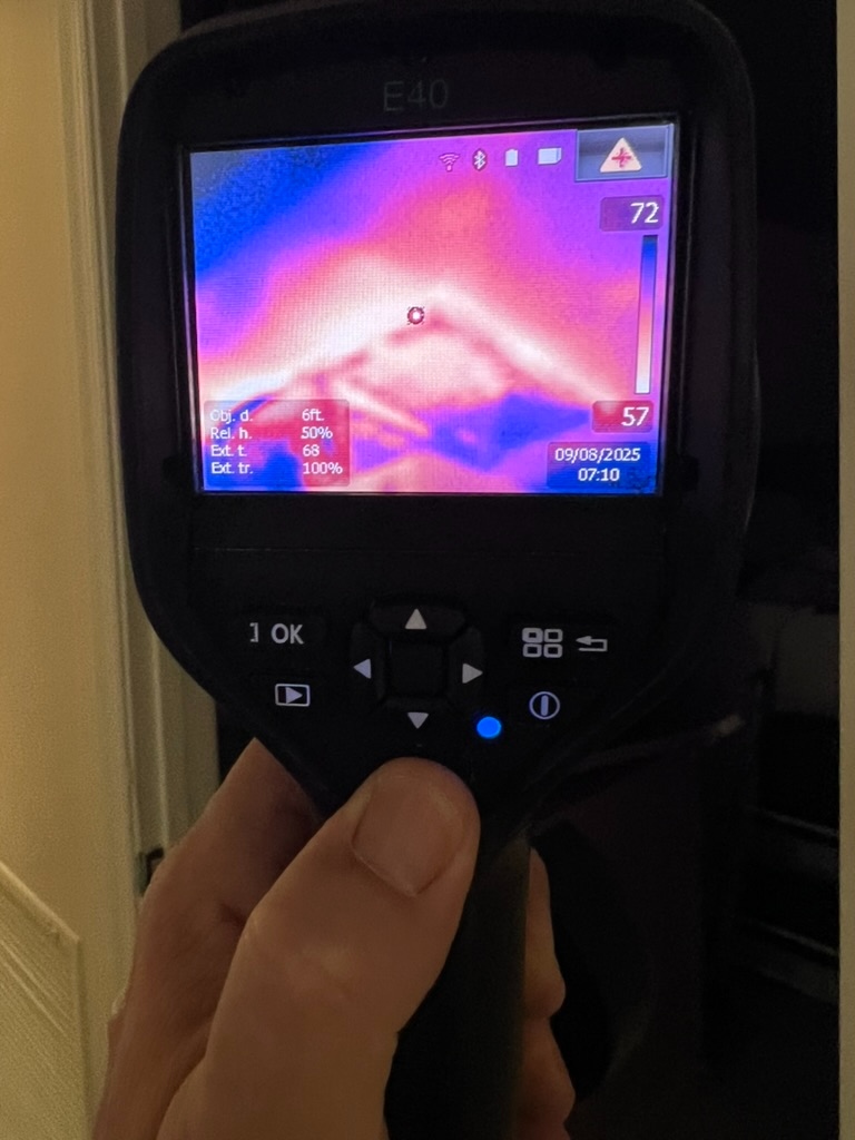 FLIR E40 thermal camera held against a wall showing a 72 degree temperature reading indicating hidden moisture