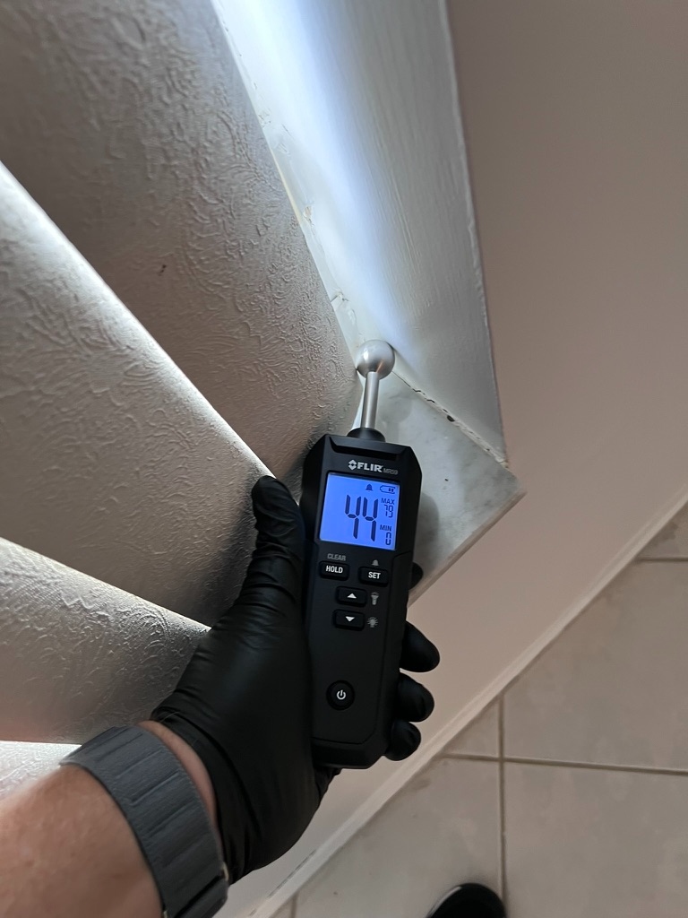 FLIR moisture meter reading elevated moisture at a bathroom ceiling and wall junction