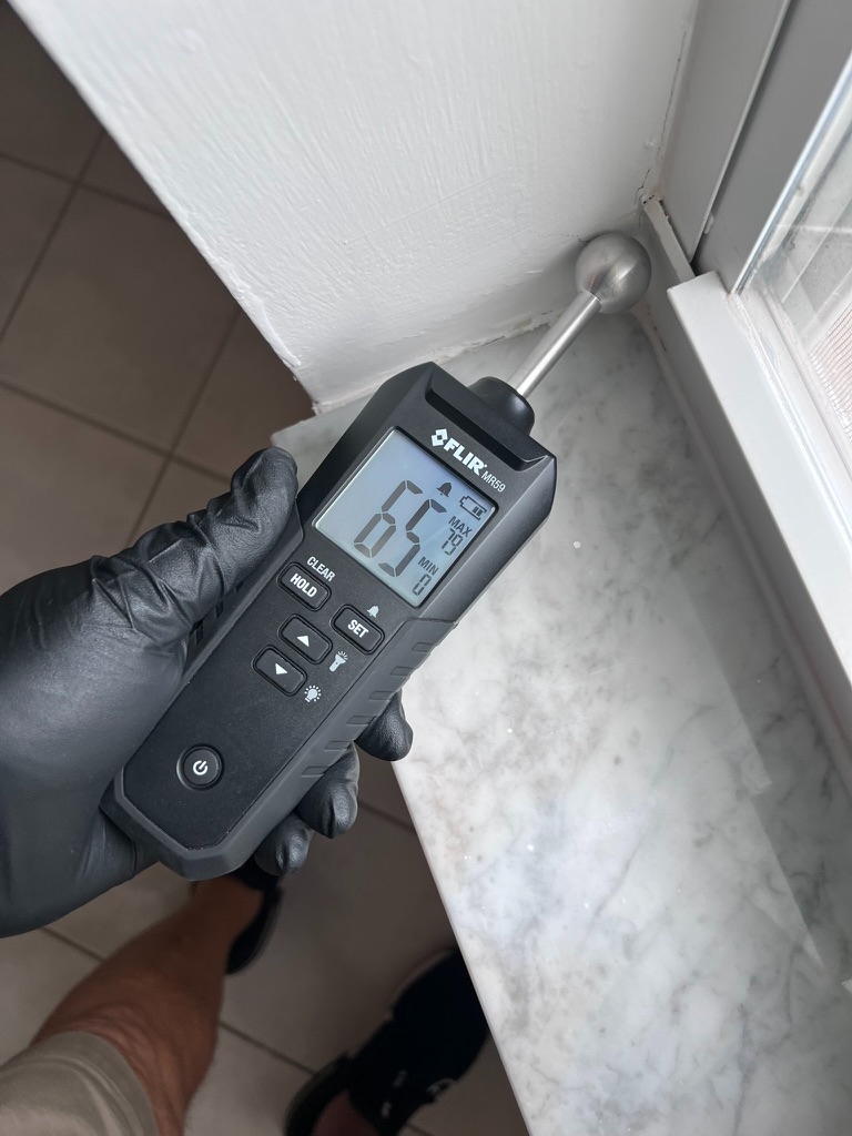 FLIR moisture meter reading elevated moisture near a window and marble sill