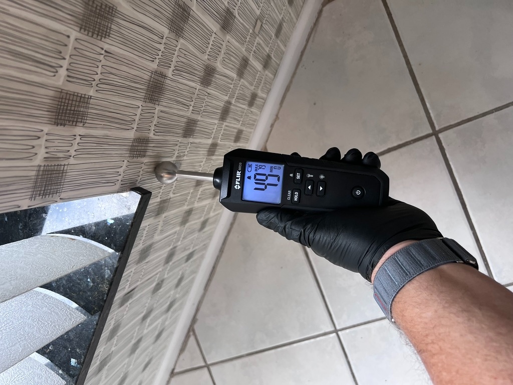 FLIR moisture meter reading moisture content on a textured ceiling near a stairwell