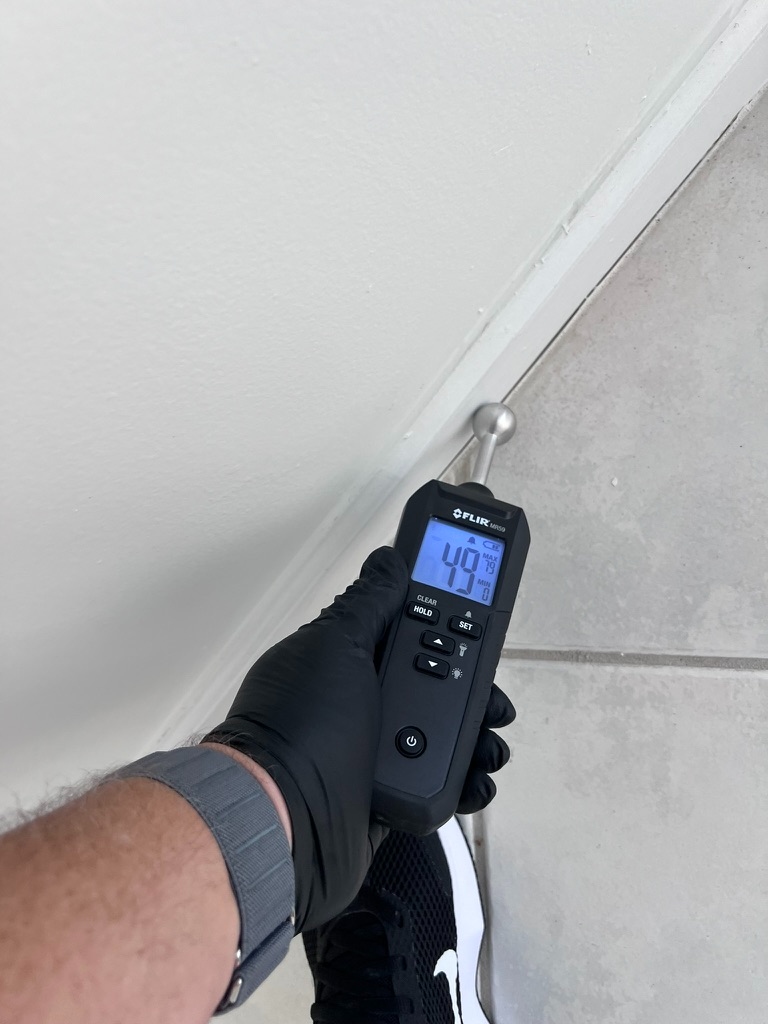 FLIR moisture meter reading moisture along a wall and ceiling trim line