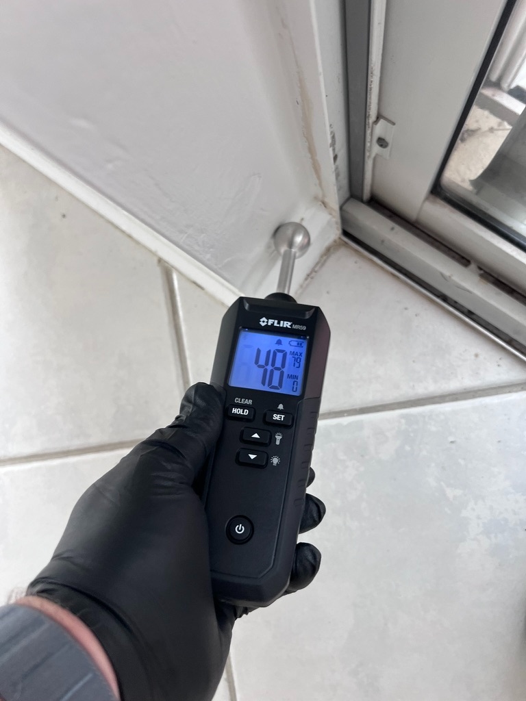 FLIR moisture meter reading elevated moisture near a sliding door frame