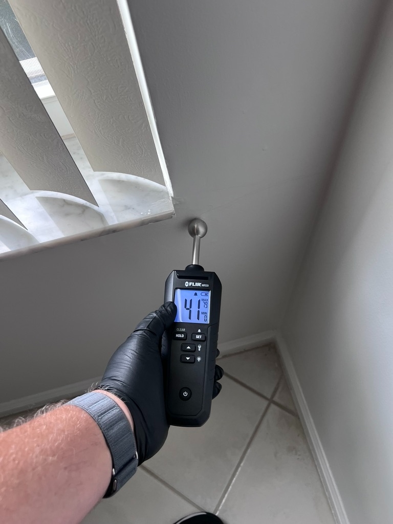 FLIR moisture meter reading moisture near a window blind and ceiling corner