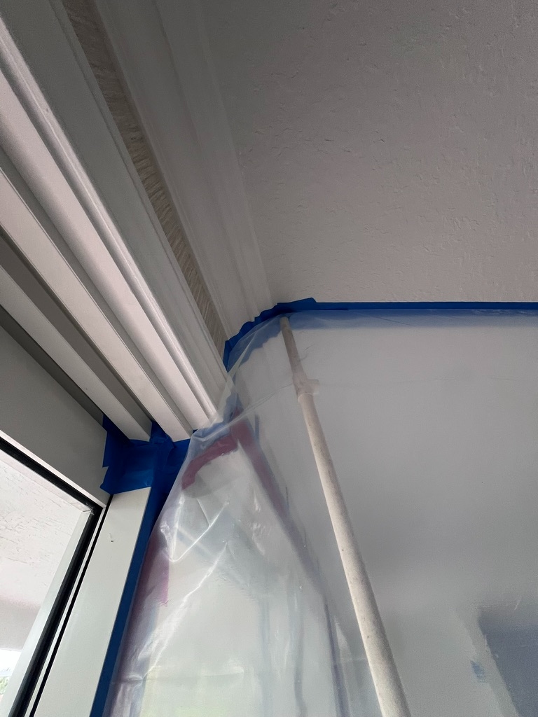 Blue tape and plastic containment setup at ceiling and doorframe