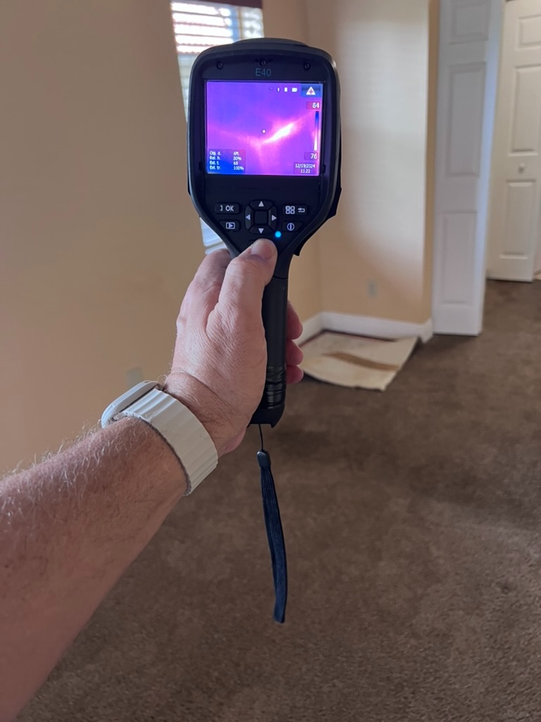 FLIR thermal camera reading a thermal anomaly on a bedroom wall near a window and doorway