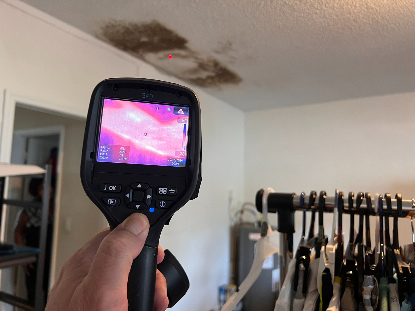 FLIR thermal camera reading a heat signature on a ceiling with visible mold staining in a closet
